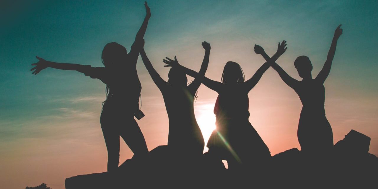 Silhouette of four women with sun background
